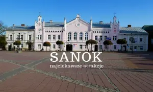 Różowy budynek ratusza na rynku w Sanoku, z napisem "Sanok najciekawsze atrakcje".