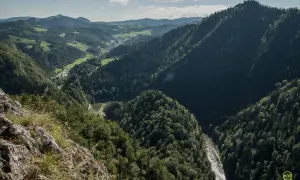 Widok z góry na dolinę rzeki i zalesione wzgórza. W oddali widać zabudowania. To idealne miejsce na sokolica trasa.