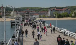 Spacer po molo w Sopocie, pełnym ludzi, to jedna z **nietypowych atrakcji Gdańska** i okolic. W tle widać plażę i zabytkowe budynki.