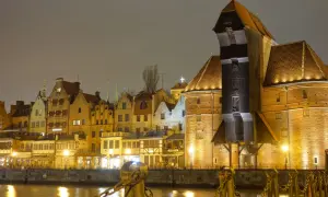 Gdańsk nocą, z Żurawiem i kamienicami odbijającymi się w wodzie.