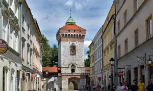 Brama Floriańska w Krakowie, majestatyczna wieża z czerwoną dachówką i kamienną fasadą, wita spacerowiczów.