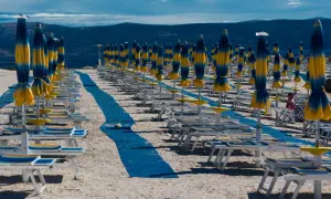 Rzędy leżaków i parasoli na plaży, jakby typowy polak na wakacjach szukał swojego miejsca.