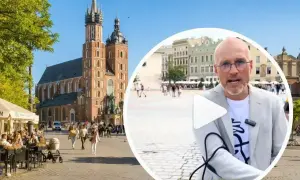 Mężczyzna w okularach opowiada o tym, czy jest krakow safe, na tle Rynku Głównego z Kościołem Mariackim.