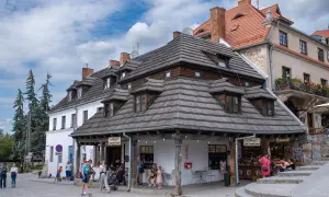 Kazimierz Dolny atrakcje: urokliwy rynek z kamieniczkami, lodziarnią i sklepikami. Ludzie spacerują, ciesząc się atmosferą.