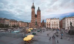 Rynek Główny w Krakowie, z Bazyliką Mariacką w centrum, to jeden z krakowskich top attractions. Ludzie spacerują, a żółte parasole tworzą barwne plamy.