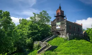 Kamienny kościół na wzgórzu, z kamiennymi schodami prowadzącymi do wejścia. Wokół bujna zieleń, idealne miejsce na odkrywanie dzierżoniów atrakcje.