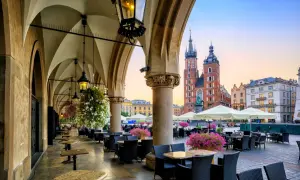 Krakowskie Sukiennice, co to? To historyczne miejsce z kawiarnianymi stolikami i widokiem na Kościół Mariacki.