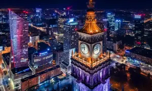 Wieżowiec z zegarami i nowoczesne budynki tworzą magiczny krajobraz warszawa nocą.