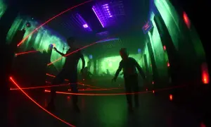 Dzieci bawią się w laserowym labiryncie w Krakowie, unikając czerwonych promieni.