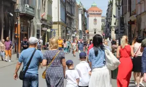 Rodzina spaceruje po urokliwych **trasach spacerowych w Krakowie**, podziwiając zabytkową architekturę i wieżę.