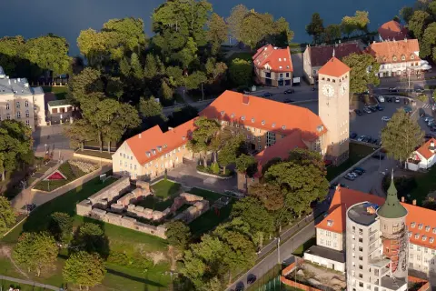Szczytna atrakcje: ruiny zamku, wieża zegarowa i budynki nad jeziorem.