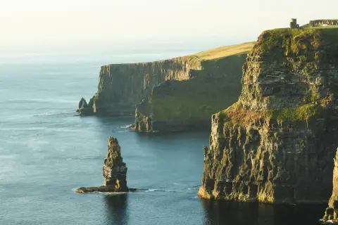 Klify Moheru – obowiązkowy punkt na mapie "Irlandia co zobaczyć". Majestatyczne skały wpadające do oceanu, z wieżą widoczną na szczycie.