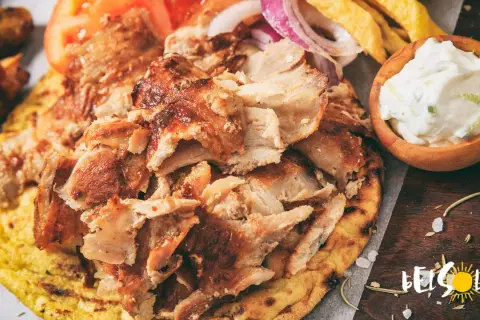 Pyszne jedzenie w Grecji: gyros z kurczaka na chlebku pita, z pomidorami, cebulą, frytkami i sosem tzatziki.
