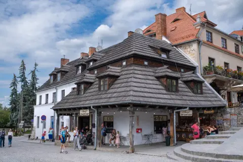 Kazimierz Dolny atrakcje: urokliwy rynek z kamieniczkami, lodziarnią i sklepikami. Ludzie spacerują, ciesząc się atmosferą.