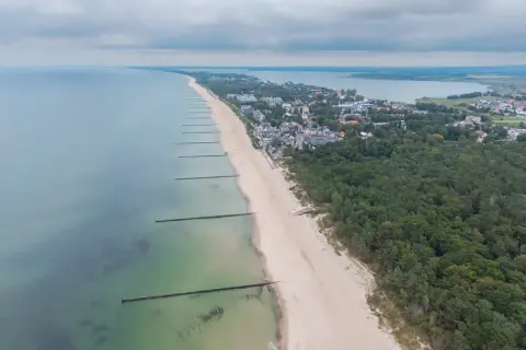 Mielno atrakcje: szeroka plaża, las sosnowy i zabudowania kurortu nad Bałtykiem. Widok z lotu ptaka na wybrzeże.
