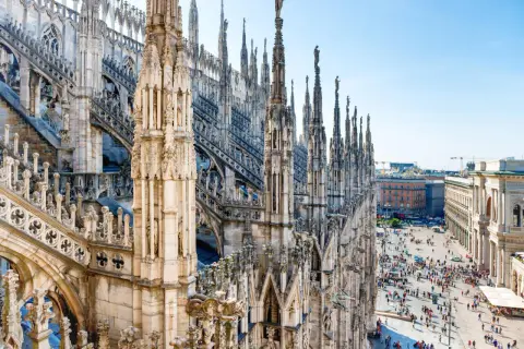 Majestatyczne iglice katedry Duomo w Mediolanie w marcu, z tłumem ludzi spacerującym po placu poniżej.