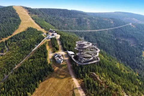 Widok na Sky Walk i wiszący most w Czechach, otoczony gęstym lasem i górskimi zboczami.