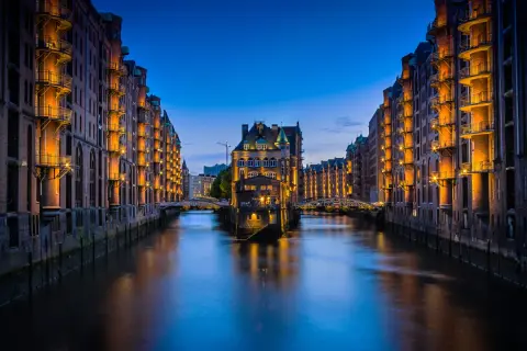Nocny widok na Speicherstadt w Hamburgu, z kanałem i zabytkowymi budynkami magazynowymi oświetlonymi ciepłym światłem. To jedna z głównych hamburg atrakcje.