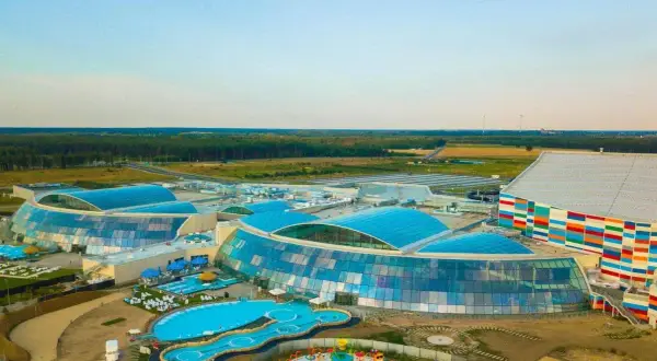 Widok z lotu ptaka na największy aqua park w Europie z błękitnymi dachami i kolorowym budynkiem.