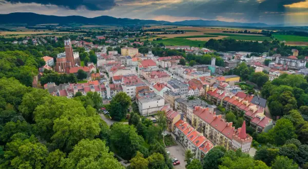 Malownicze polskie Carcassonne z dominującą wieżą kościelną, otoczone zielenią i górami.