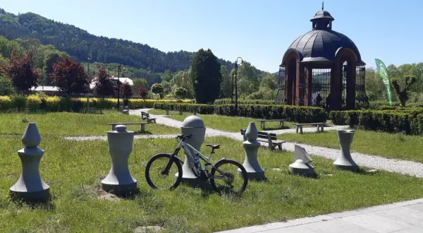 Rower czeka na przygodę na trasie w Muszynie, wśród kamiennych figur i zieleni.