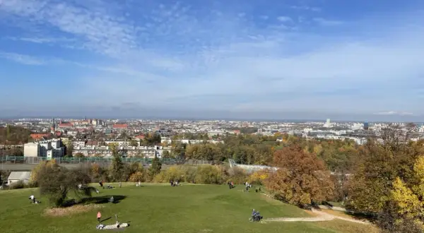 Jesienny dzień w Krakowie. Ludzie odpoczywają na zielonej trawie, a w tle rozciąga się panorama miasta.