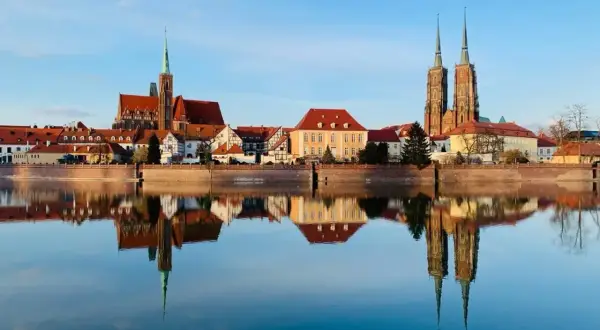 Wrocław wydarzenia na weekend: Katedra i zabytkowe kamieniczki odbijają się w spokojnej tafli Odry.