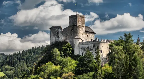 Zamek w Niedzicy, jedna z głównych atrakcji Nowego Targu, majestatycznie wznosi się na wzgórzu, otoczony zielenią.