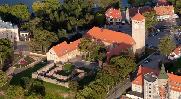 Szczytna atrakcje: ruiny zamku, wieża zegarowa i budynki nad jeziorem.
