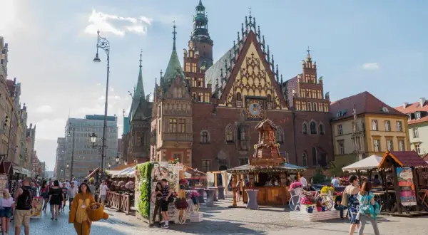 Tętniący życiem Rynek we Wrocławiu, z pięknym Ratuszem i kramami pełnymi kwiatów. Wspaniałe wrocławskie atrakcje w letnim słońcu.
