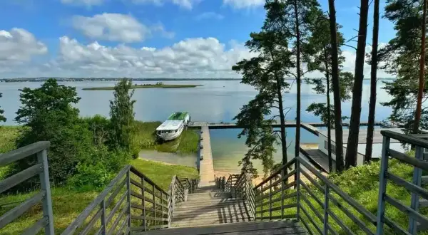 Idealne miejsce na mazury na weekend. Drewniane schody prowadzą do jeziora, gdzie cumuje statek.