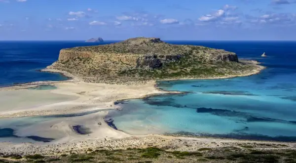 Malownicza zatoka z turkusową wodą i piaszczystą plażą, otoczona skalistymi klifami. To raj dla miłośników przyrody, ukazujący walory przyrodnicze Grecji.