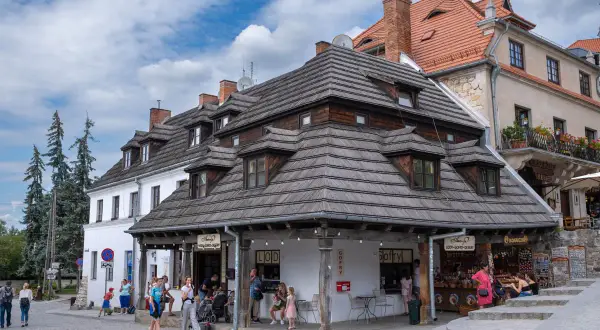 Kazimierz Dolny atrakcje: urokliwy rynek z kamieniczkami, lodziarnią i sklepikami. Ludzie spacerują, ciesząc się atmosferą.