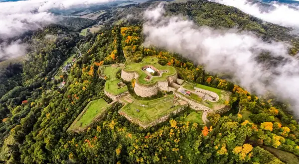 Fortecę na wzgórzu otaczają jesienne lasy. Srebrna Góra oferuje wspaniałe widoki i historyczne atrakcje.
