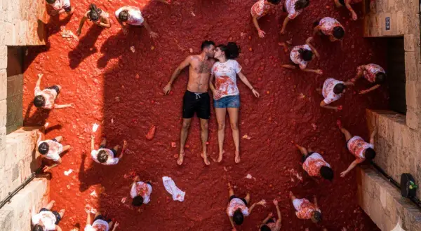 Para zakochanych całuje się pośród tłumu ludzi rzucających pomidorami podczas La Tomatina w Hiszpanii.