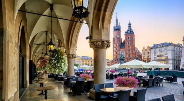 Krakowskie Sukiennice, co to? To historyczne miejsce z kawiarnianymi stolikami i widokiem na Kościół Mariacki.