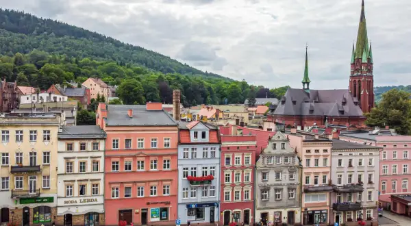 Kolorowe kamienice i kościół z zieloną wieżą tworzą malowniczy krajobraz. Odkryj teraza ruda atrakcje, spacerując po urokliwym rynku.