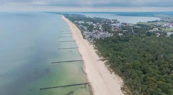 Mielno atrakcje: szeroka plaża, las sosnowy i zabudowania kurortu nad Bałtykiem. Widok z lotu ptaka na wybrzeże.