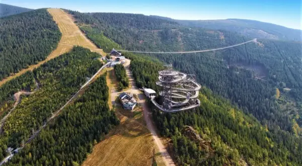 Widok na Sky Walk i wiszący most w Czechach, otoczony gęstym lasem i górskimi zboczami.