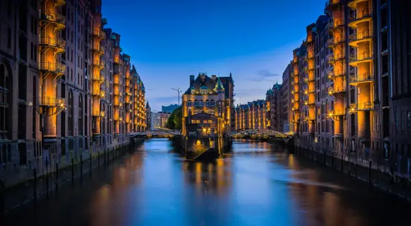 Nocny widok na Speicherstadt w Hamburgu, z kanałem i zabytkowymi budynkami magazynowymi oświetlonymi ciepłym światłem. To jedna z głównych hamburg atrakcje.