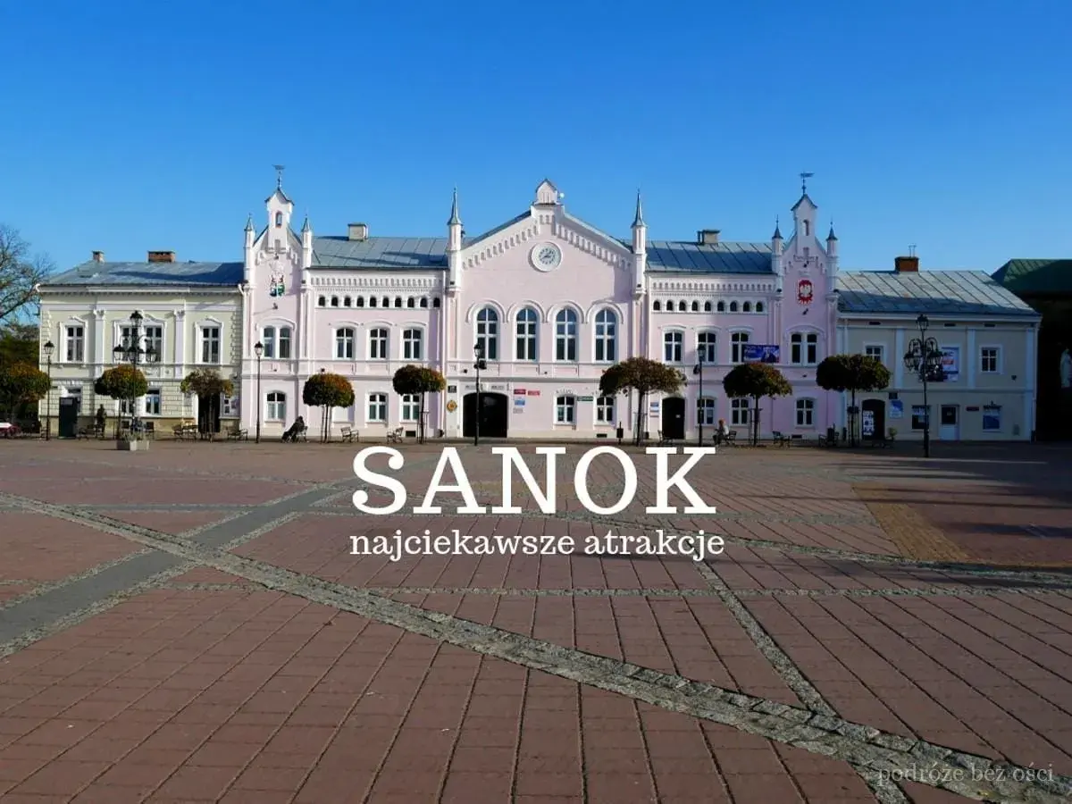 Różowy budynek ratusza na rynku w Sanoku, z napisem "Sanok najciekawsze atrakcje".