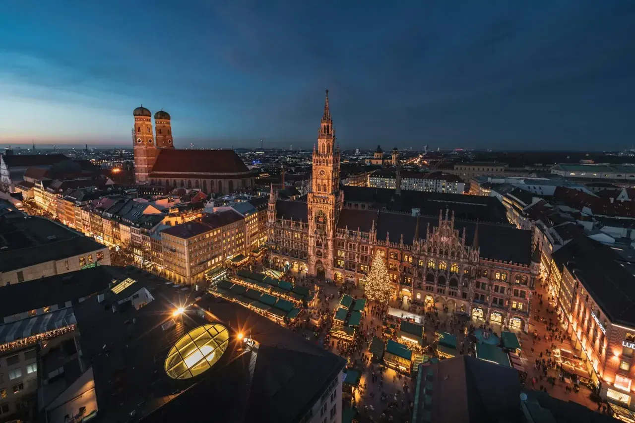 Nocne monachium zwiedzanie: Rynek Główny z jarmarkiem bożonarodzeniowym, Nowy Ratusz i Frauenkirche w blasku świateł.