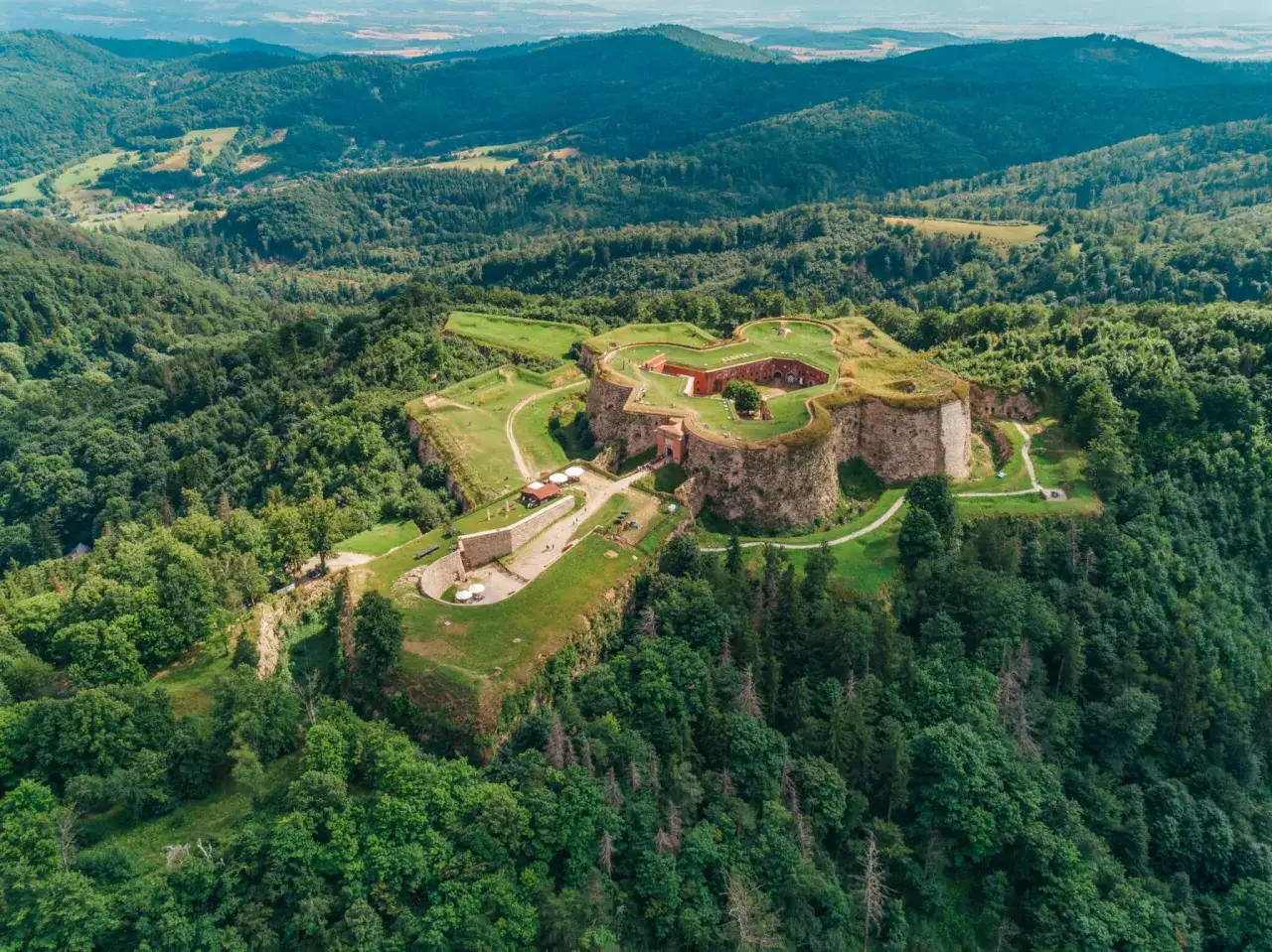 Forteca w Srebrnej Górze, jedna z największych atrakcji Kotliny Kłodzkiej, otoczona zielonymi wzgórzami.