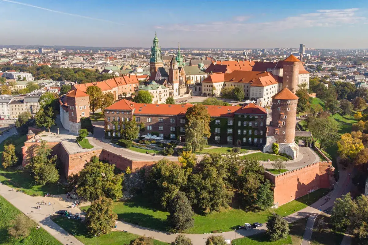Wawel – królewski zamek i katedra, ikoniczne kraków zabytki, otoczone zielenią i rozległym miastem.