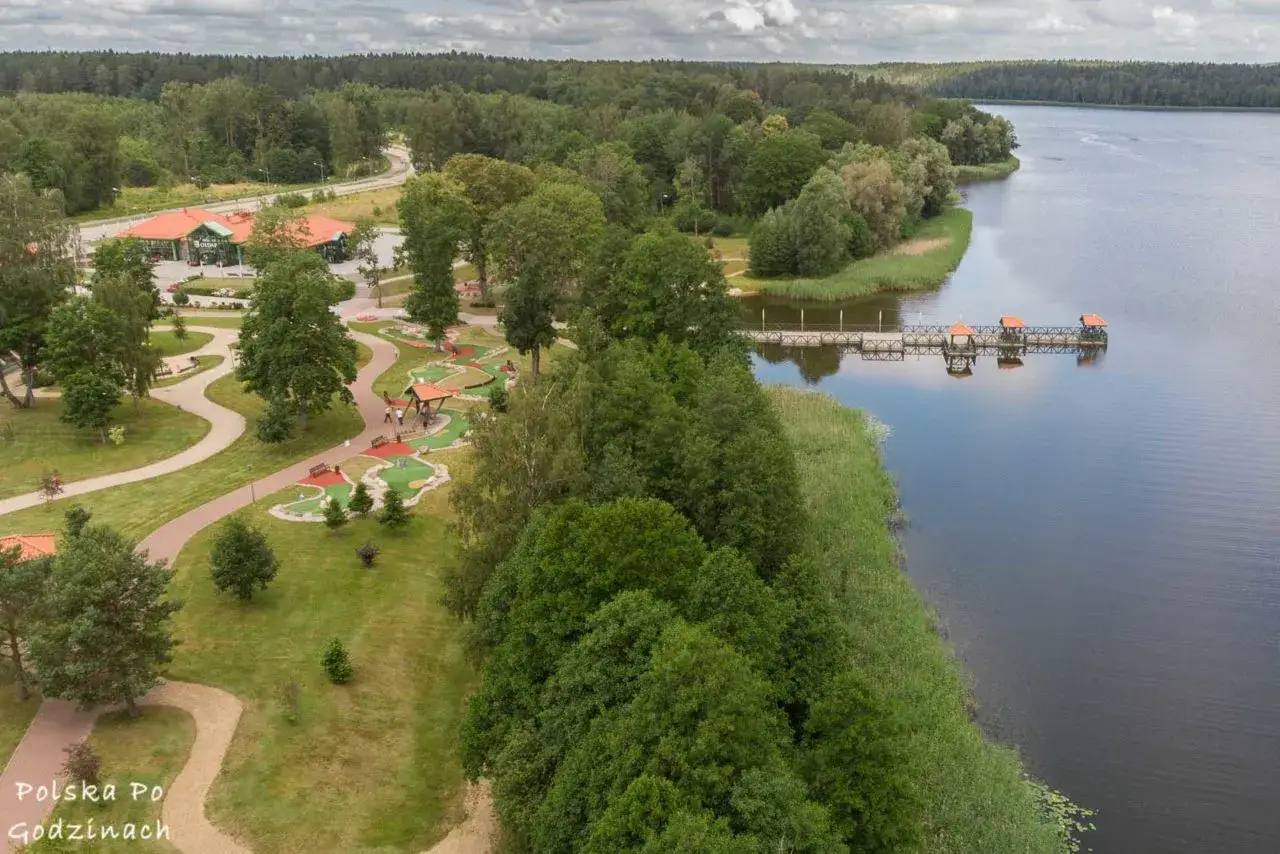 Gołdap atrakcje: malowniczy teren rekreacyjny nad jeziorem z mini golfem, pomostem i budynkiem restauracyjnym.