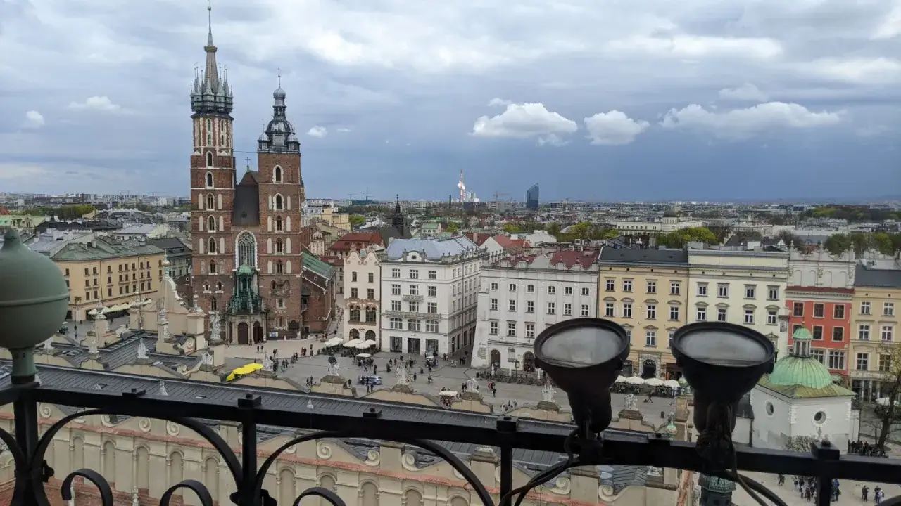 Widok na Rynek Główny w Krakowie z wieżą ratuszową w tle. W oddali widać panoramę miasta.