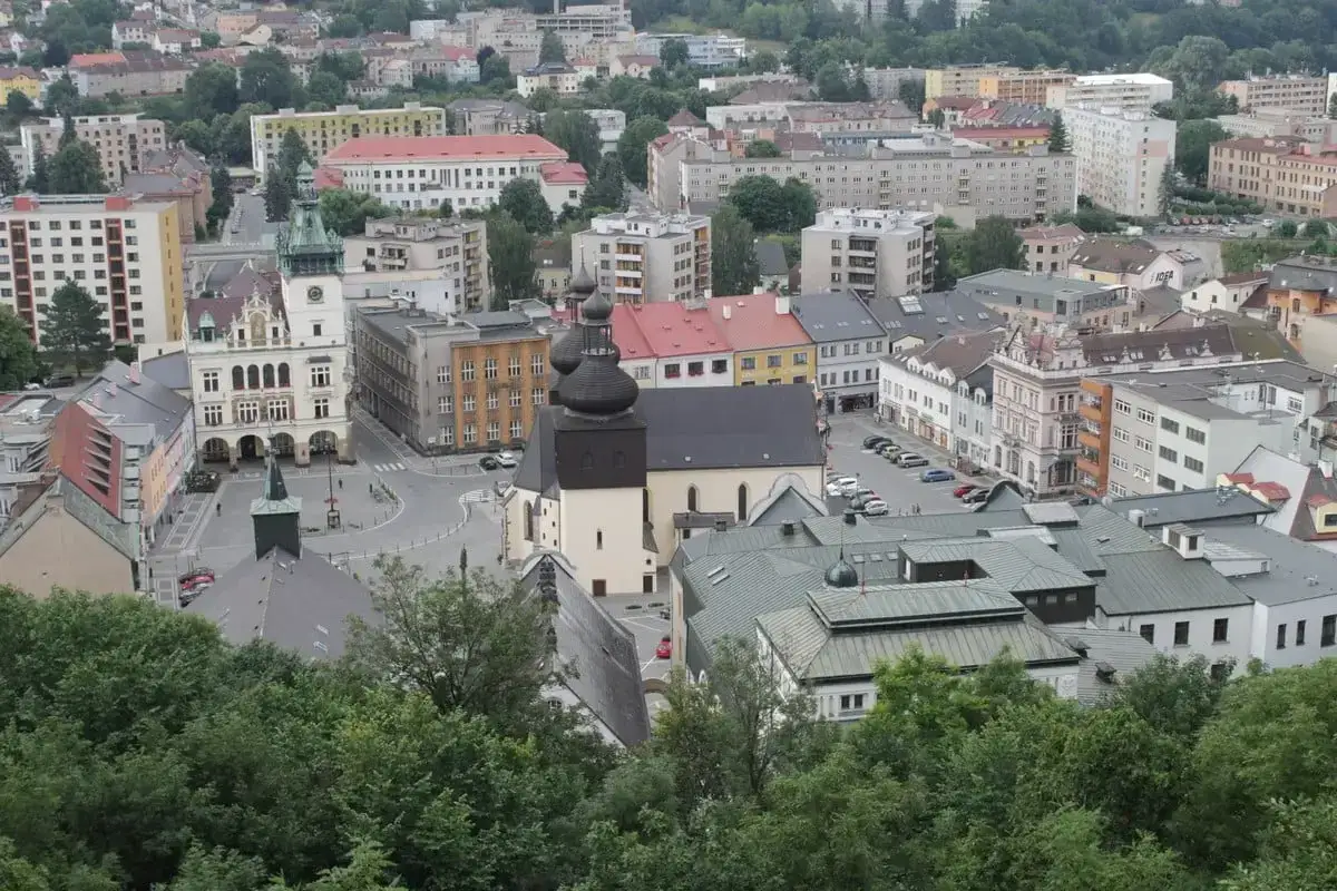 Widok na miasto z wieżą ratuszową i kościołem, zalesione wzgórza w tle. To urokliwy zakątek Czech, gdzie nachod Czechy zaprasza do odkrywania historii.