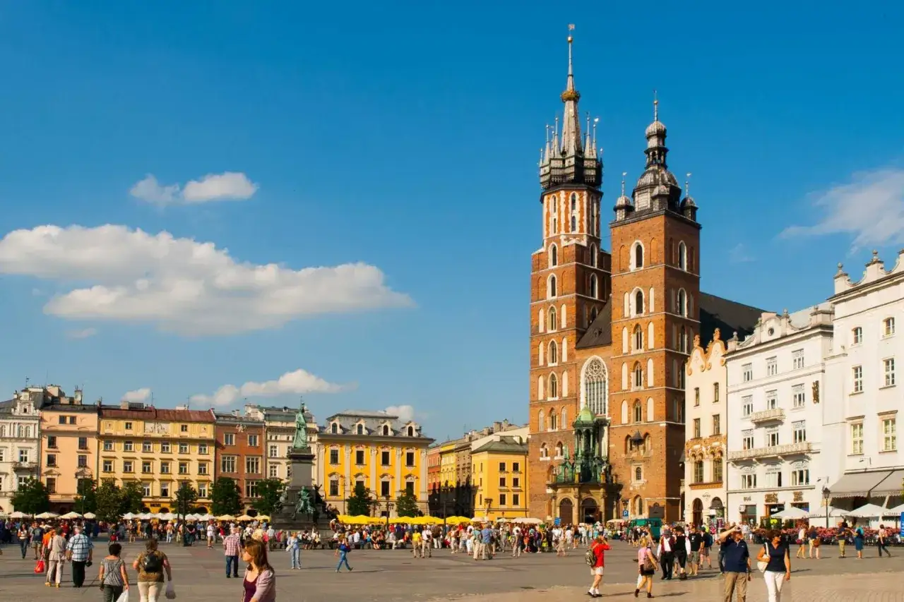 Tłum ludzi na Rynku Głównym w Krakowie, podziwiający Bazylikę Mariacką. Wspaniałe widoki, co w Krakowie!