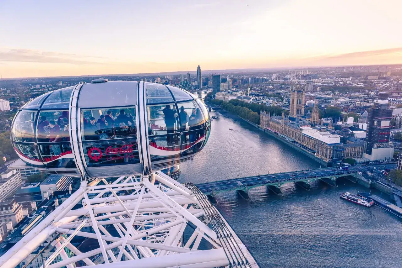 Widok z kapsuły London Eye na Tamizę i Parlament. Zachodzące słońce maluje niebo na ciepłe barwy.
