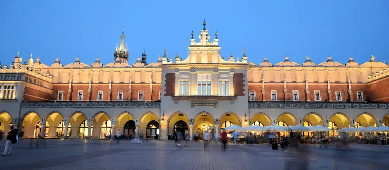 Krakowskie Sukiennice, co to za budynek? To historyczne centrum handlu na Rynku Głównym, tętniące życiem wieczorem.